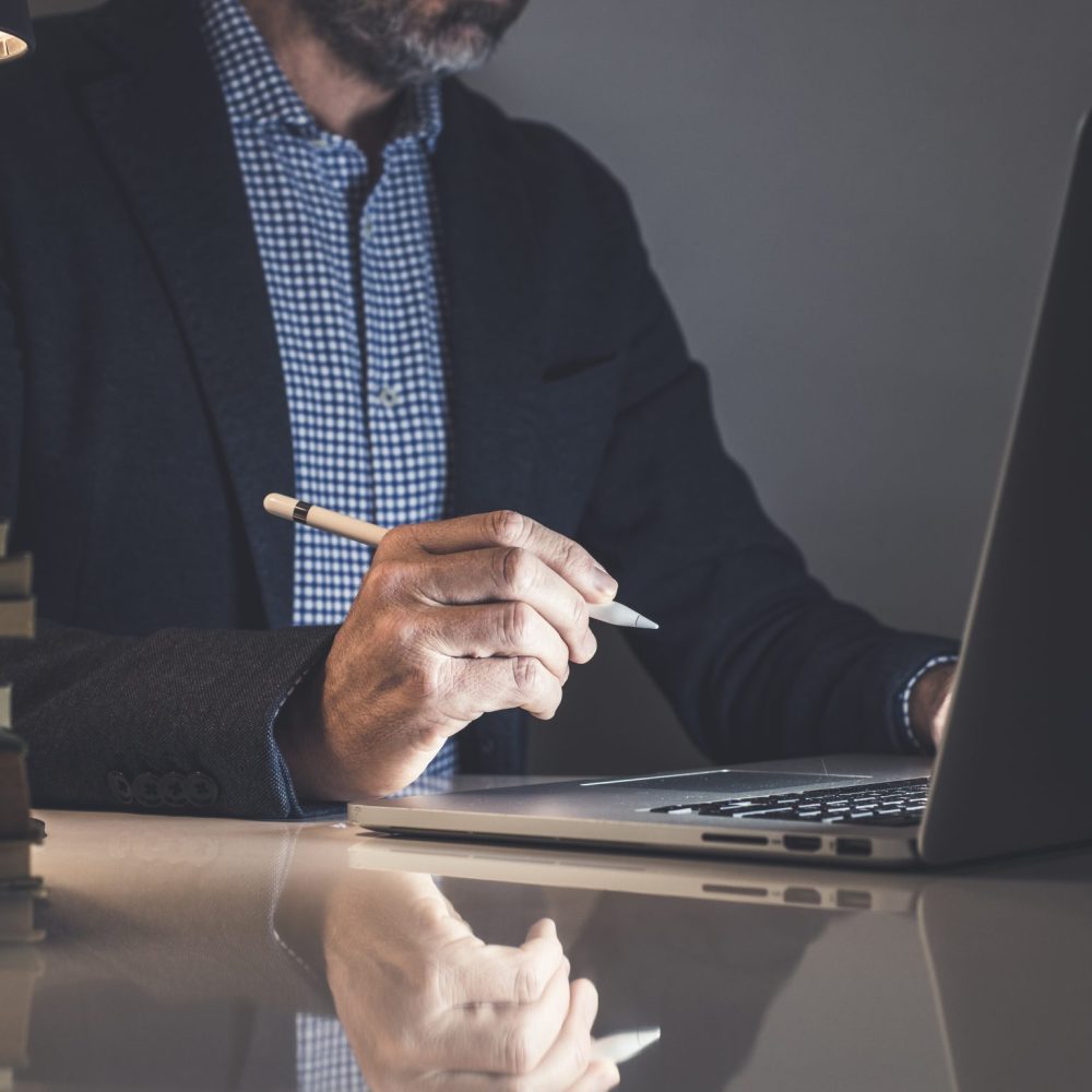 Businessman working with laptop and tablet sitting at the desk. Man write with electronic stylus pen